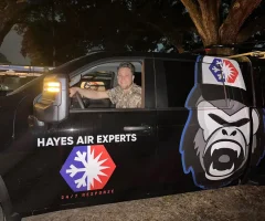 A man smiling in driver's seat of a Hayes Air Experts service truck with gorilla logo at night.