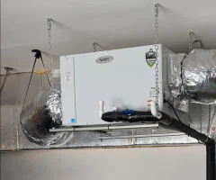 Aprilaire ventilation unit suspended from ceiling with insulated ductwork, PVC pipes and hanging chains