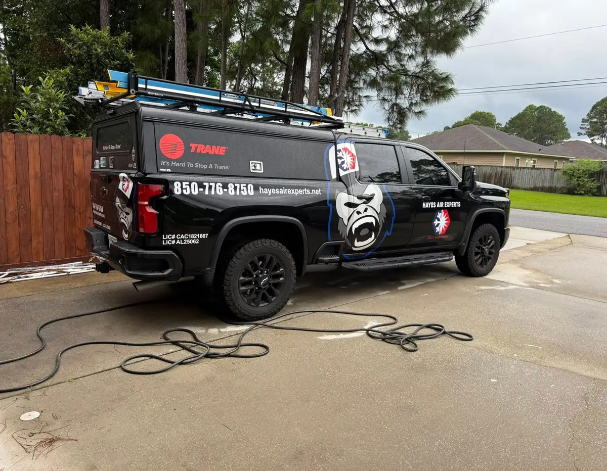 Black Hayes Air Experts service truck with Trane logo and ladders parked on driveway