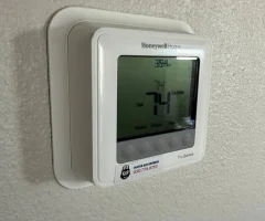 Honeywell Home digital thermostat ProSeries mounted on textured wall displaying 74°F in cooling mode.